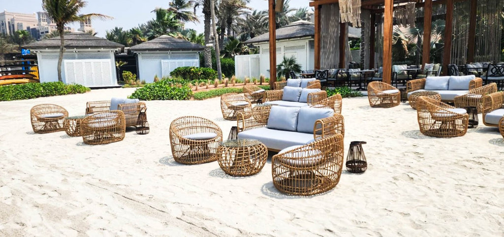 Beach lounge furnished with 2-seater sofas, round lounge chairs and side tables at French Riviera Beach Restaurant in Dubai