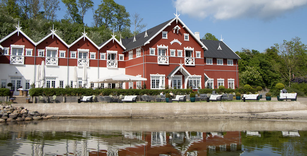 Danish Dyvig Badehotel, a historical red building with white exteriors, outdoor lounge in the foreground