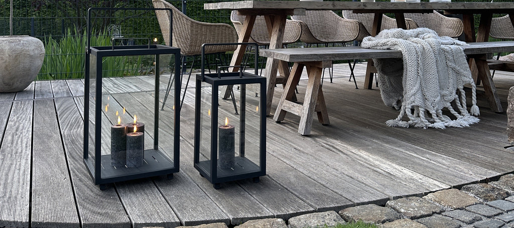 Two black lanterns with grey candle light outdoors