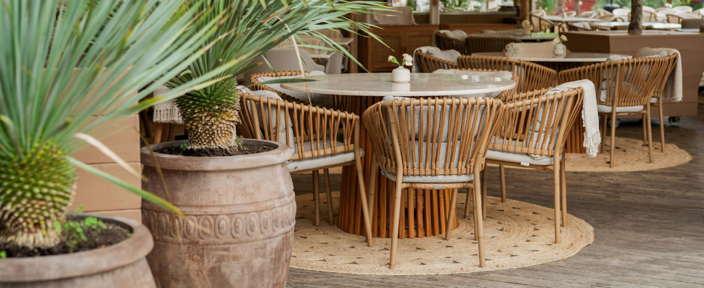 Josefina Restaurant interior with modern bohemian style with round table and Cane-line Ocean chair with palms on the side