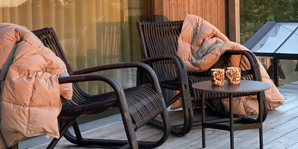 Two Curve lounge chairs in black with cushions and Twist side table with coffee cups