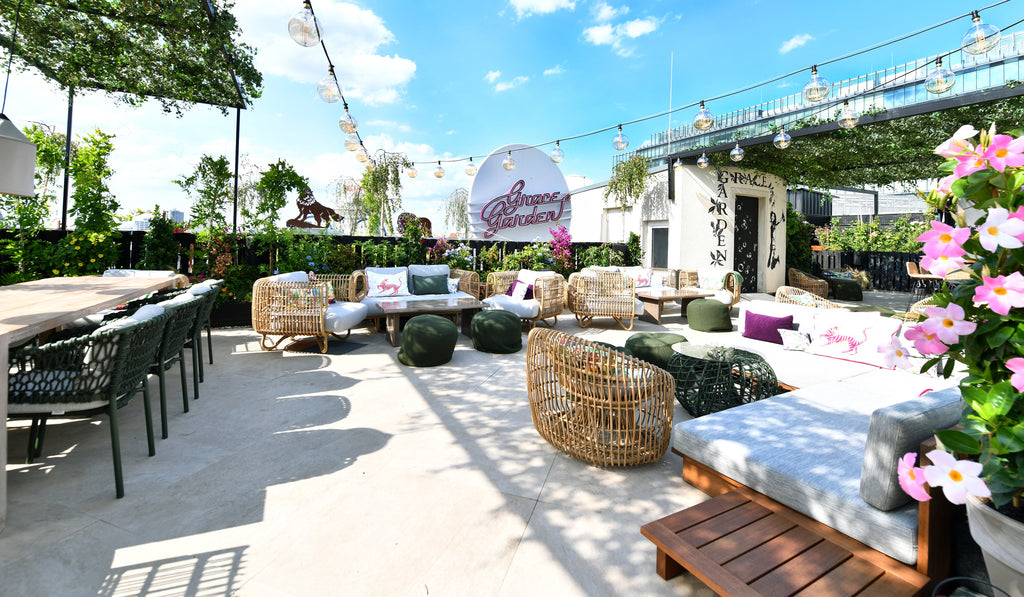Grace Garden roofttop bar and lounge atop Hotel Zoo Berlin, pink blooming flowers, Dark green Cane-line Ocean outdoor dining chairs, Cane-line Nest round chair and lounge chair in nature