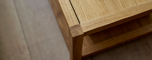 Close-up of a wooden coffee table showing a smooth surface and sturdy legs, highlighting craftsmanship and natural design elements.