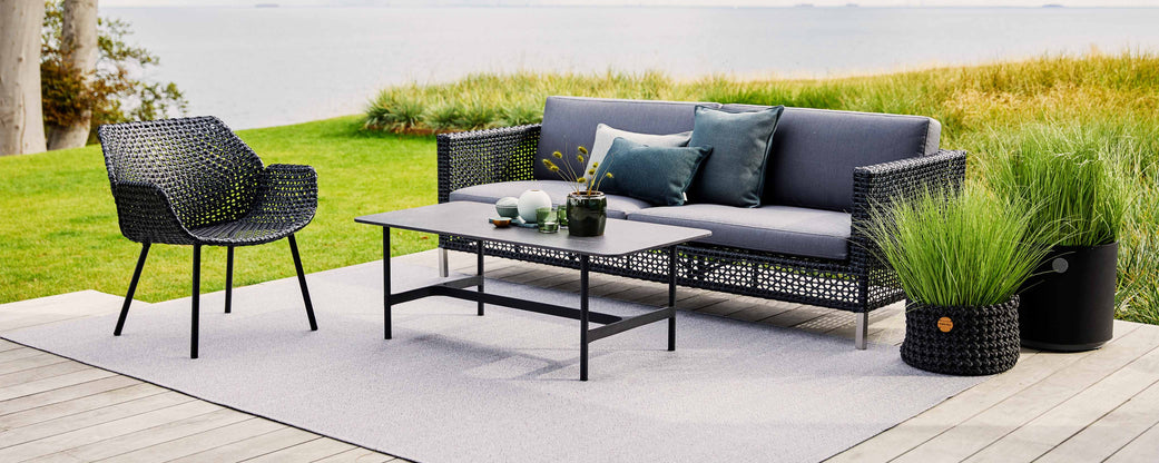 Stylish seating arrangement featuring a modern sofa, armchair, and coffee table, complemented by decorative cushions and greenery.