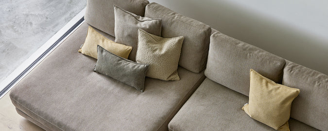 A stylish arrangement of various scatter cushions in earthy tones, adding comfort and texture to a plush seating area.