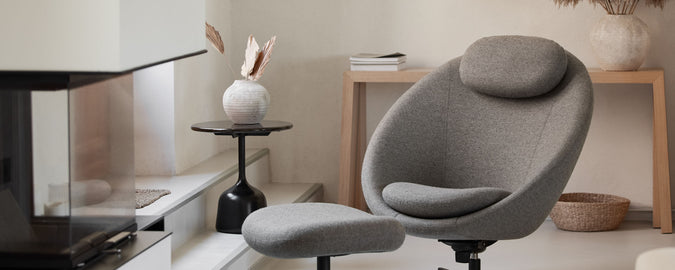 Cozy gray chair with a matching footrest beside a modern table and decorative elements, creating a stylish and inviting space.