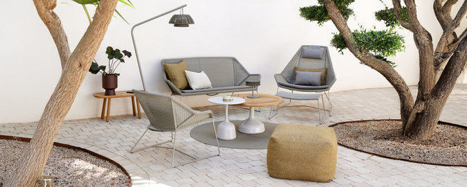 Modern lounge setting featuring a grey sofa, grey chair, wooden coffee table, and yellow pouf.