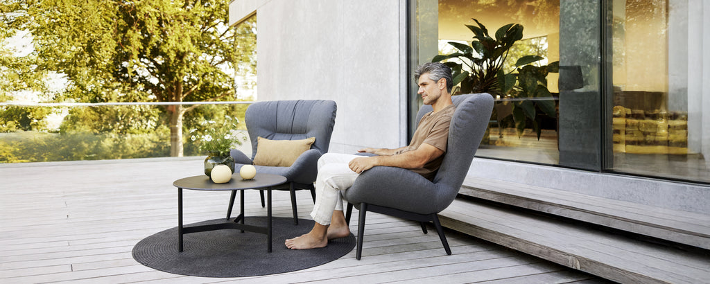 Modern lounge area featuring grey armchairs, a black table, and a round rug.