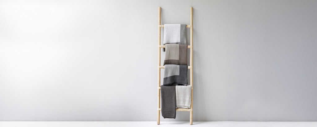 Modern towel ladder displaying beige, grey, and white towels.
