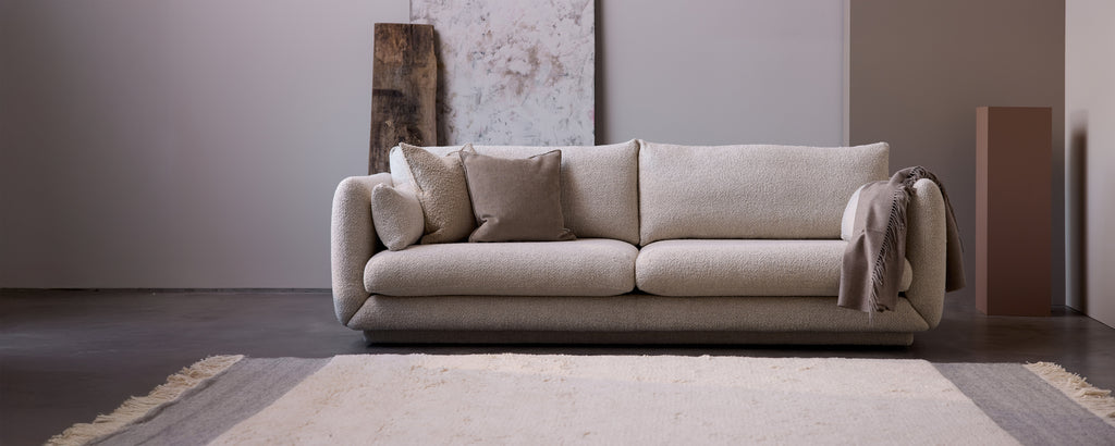 Beige sofa with grey cushions in a modern lounge setting.