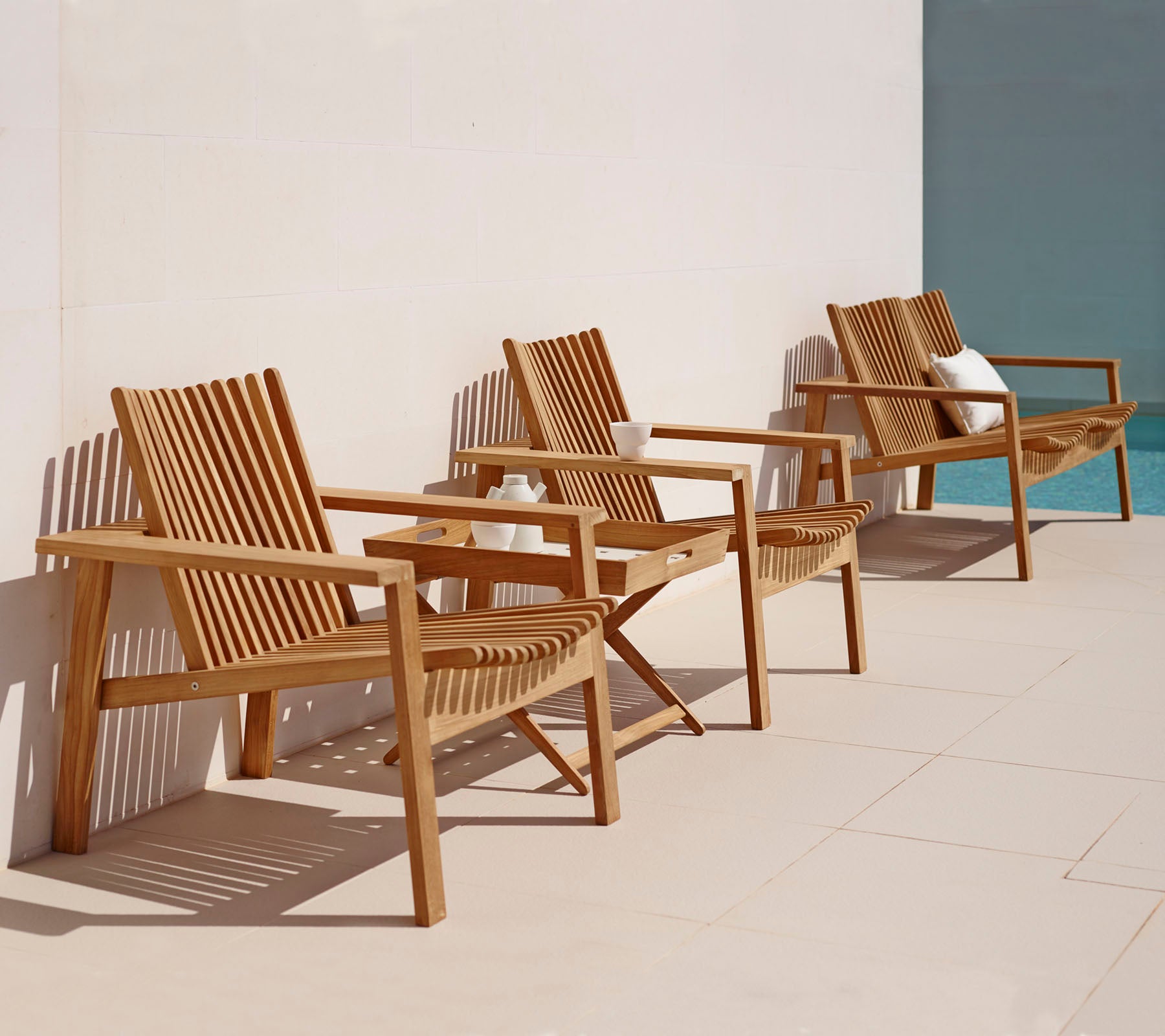 Three wooden lounge chairs with slatted designs arranged in a row, featuring a simple, elegant style suitable for relaxation.