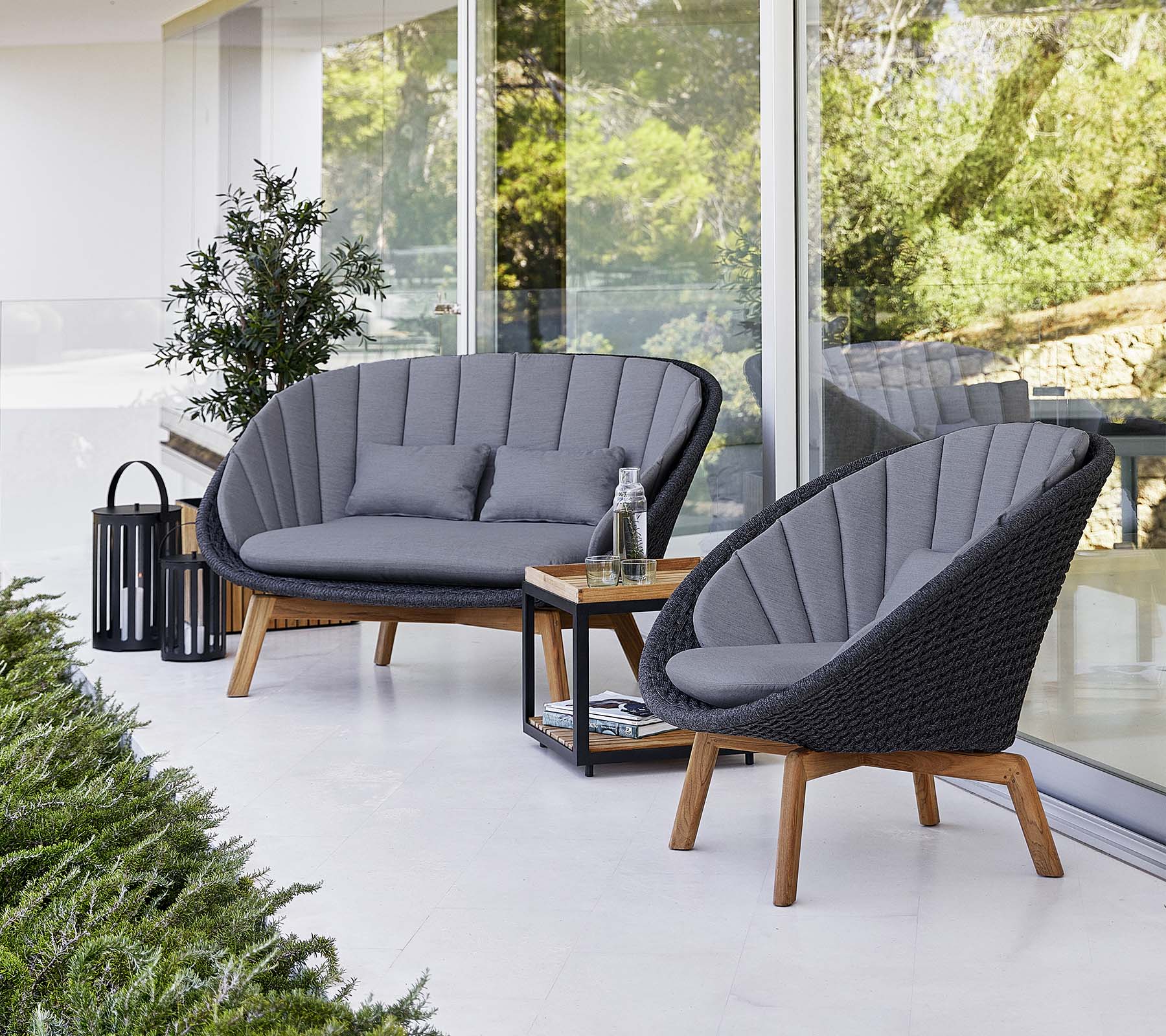 Stylish outdoor seating with two cushioned chairs and a loveseat, accompanied by a small table and a decorative lantern.