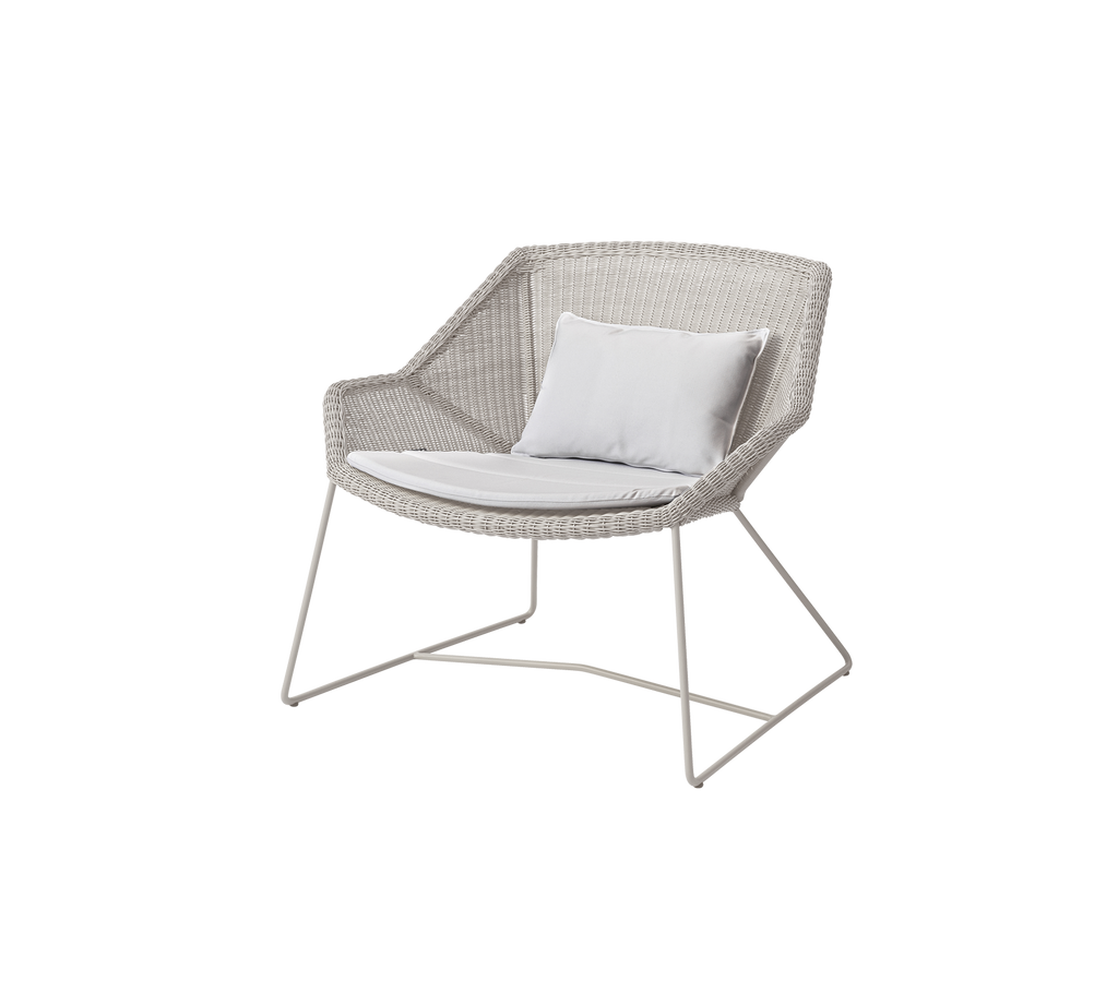 Modern white chair with a white cushion in a lounge setting.