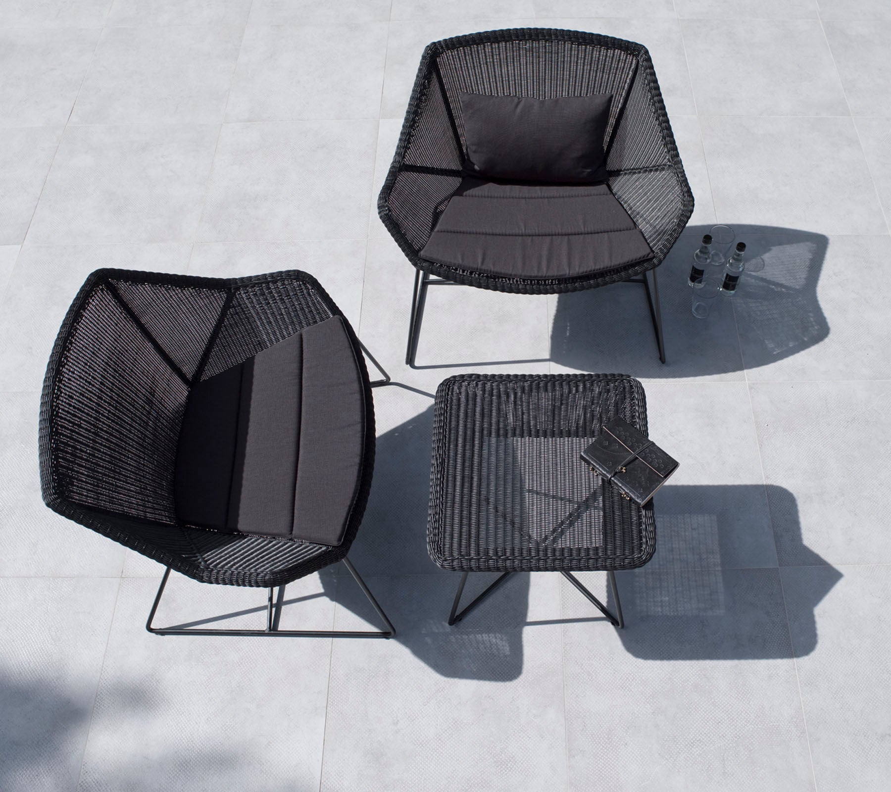Stylish outdoor seating set featuring two hexagonal chairs and a square table, all in black with minimalist design.
