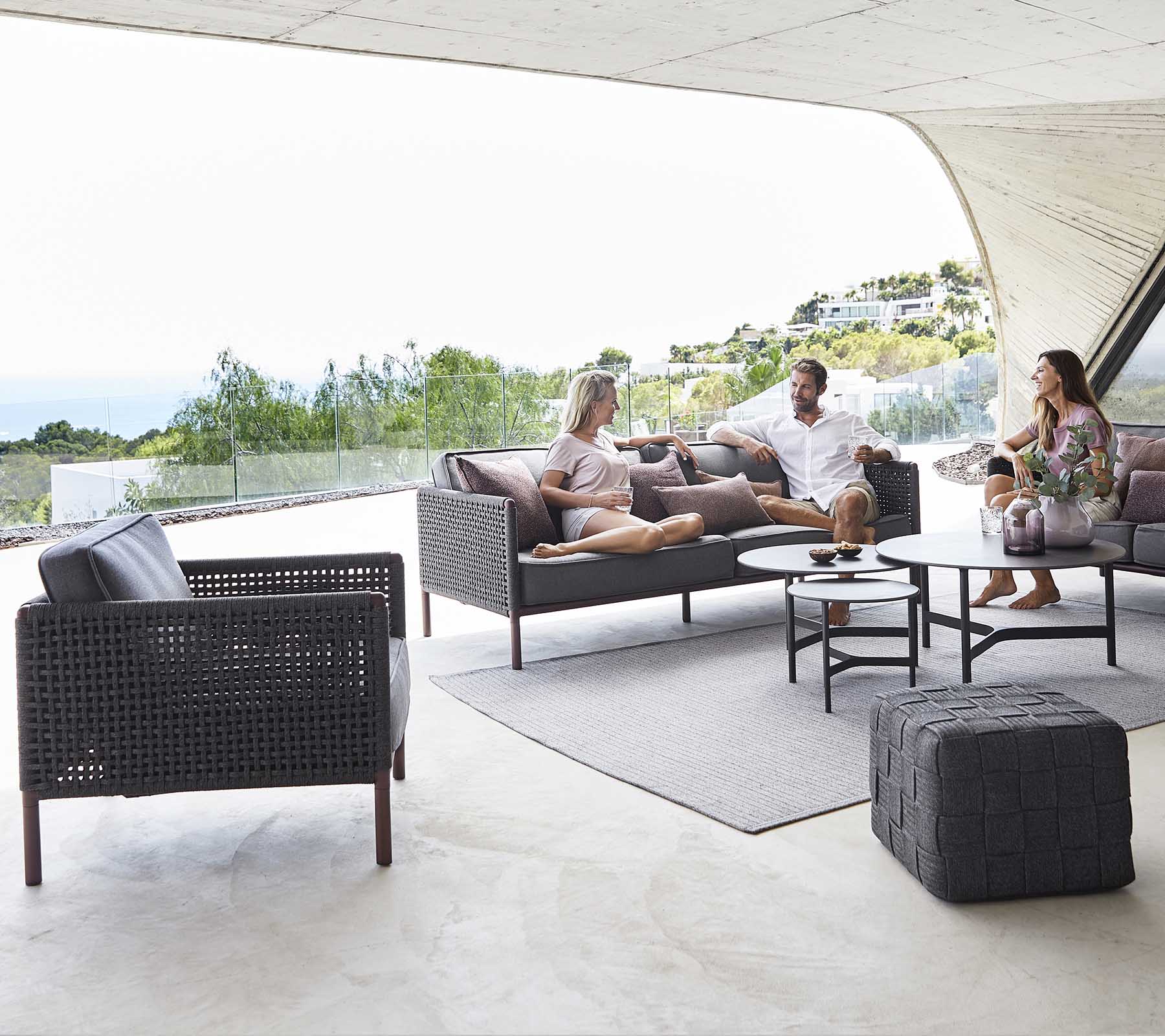 A cozy seating area featuring a coffee table, stylish chairs, and people enjoying a relaxed conversation with a scenic backdrop.
