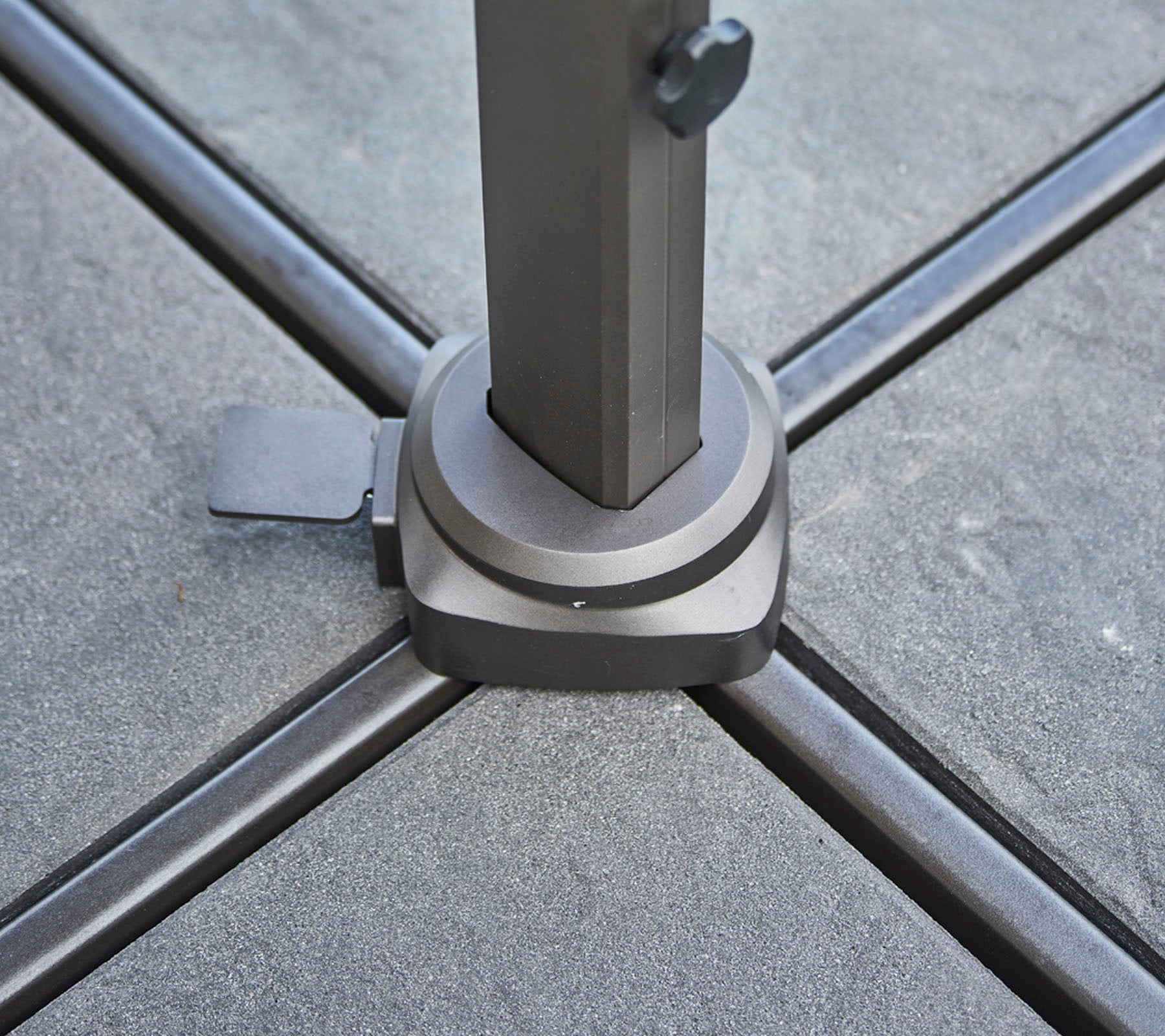 Base of a sturdy umbrella pole with a locking mechanism, designed for stability and support on a flat surface.