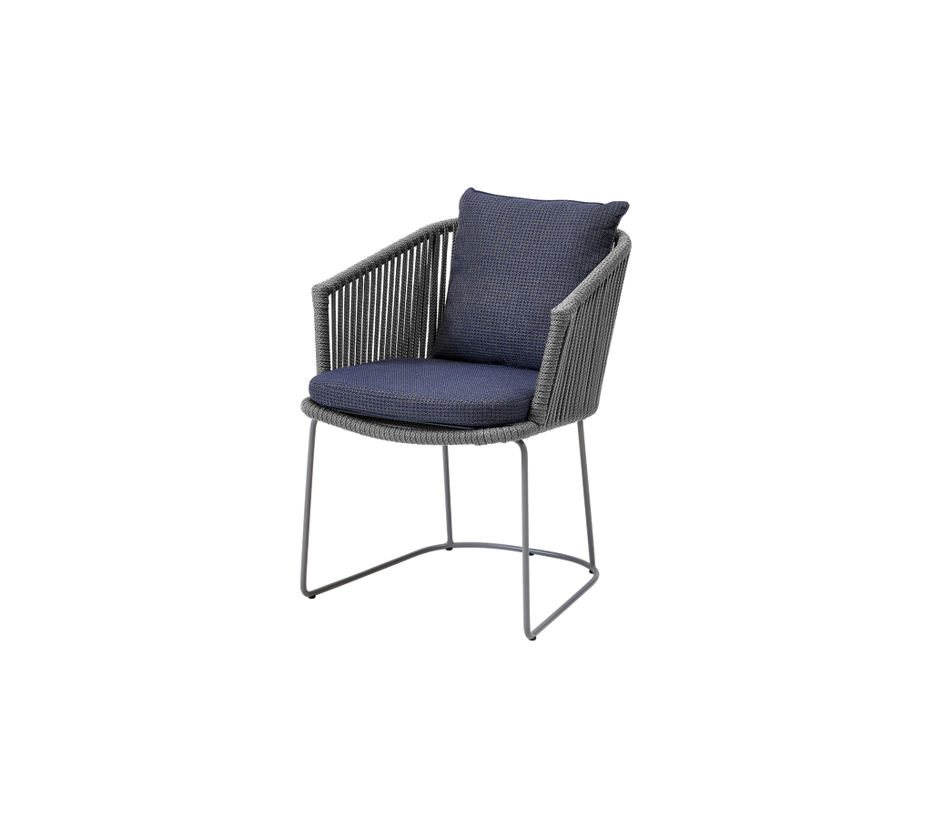 Gray wicker chair with a dark blue cushion and backrest, suitable for indoor or outdoor use.