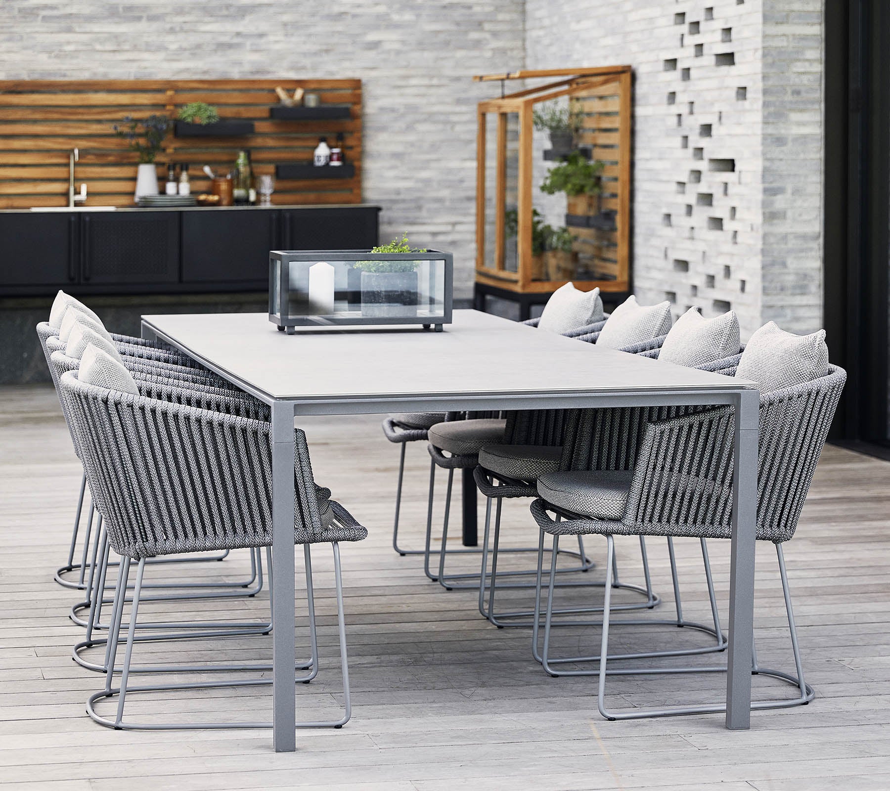 A modern dining table with gray metal frame and comfortable chairs, featuring soft cushions and a minimalist design, perfect for gatherings.