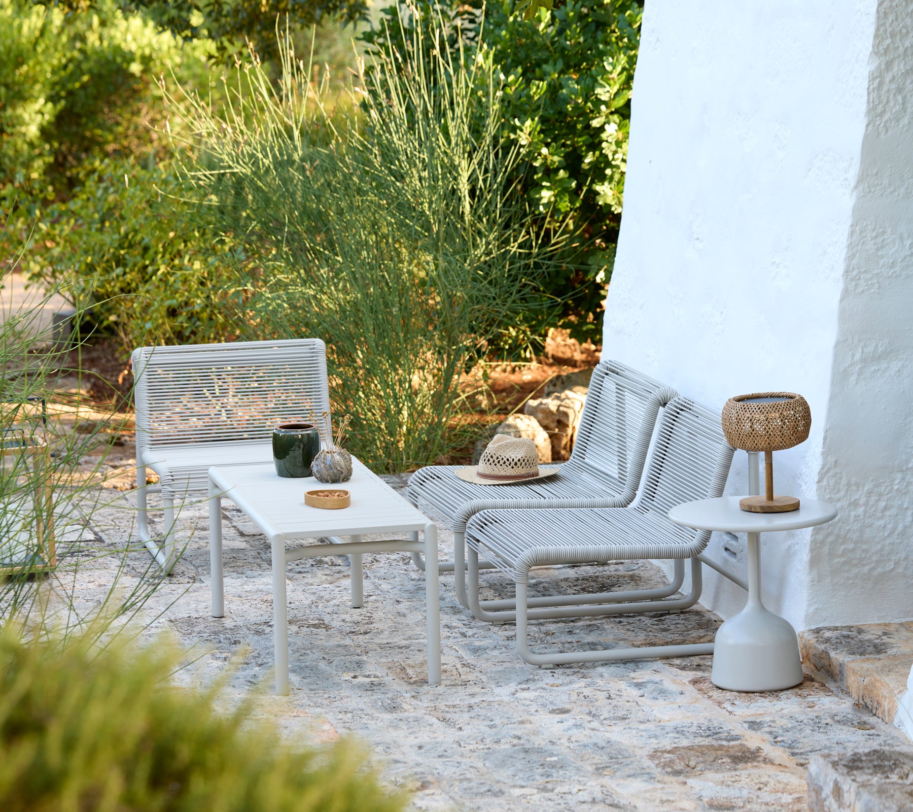 Modern grey lounge chairs and white tables in a minimalist outdoor setting.