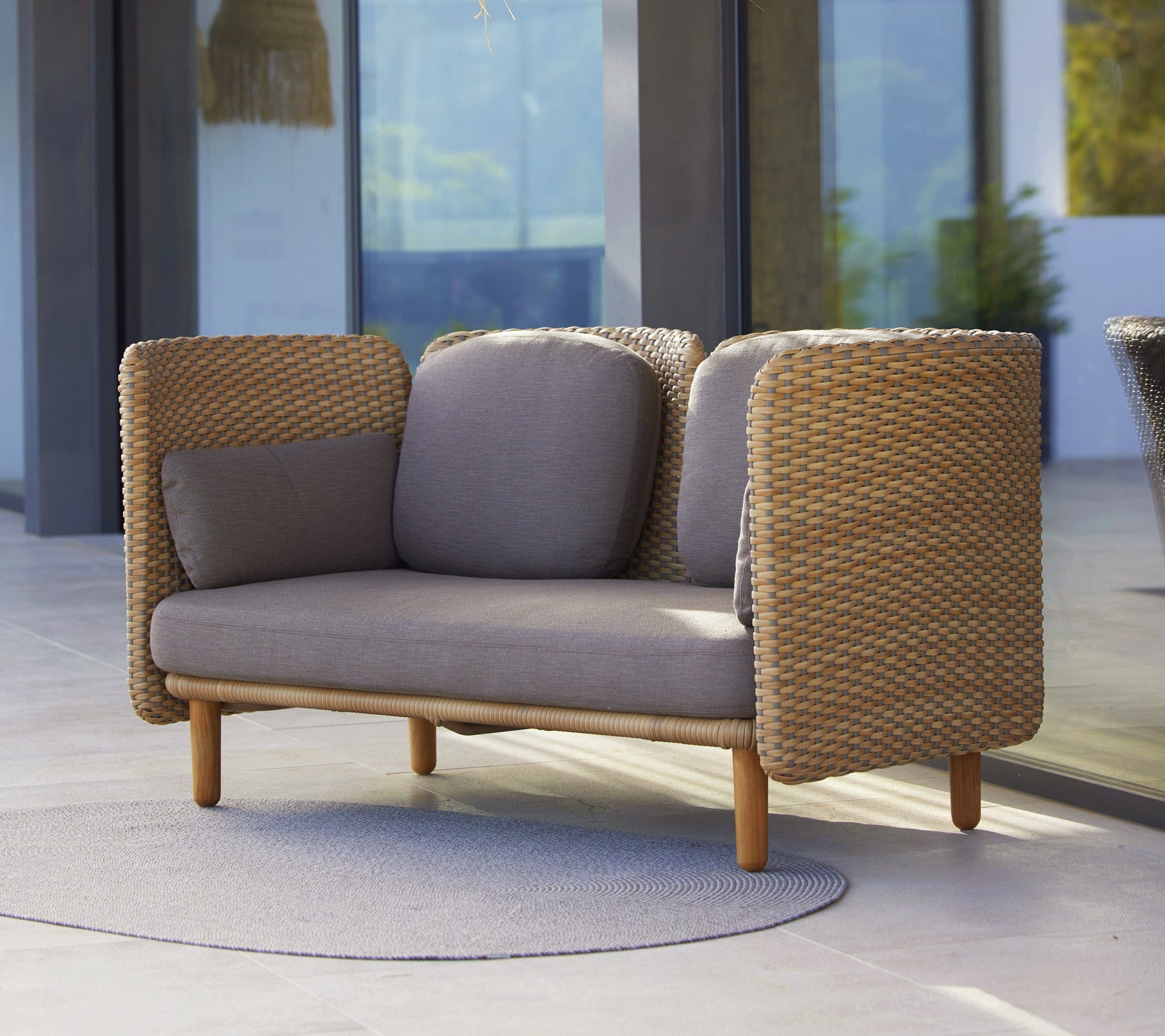 Arch 2-seater sofa featuring a low backrest, woven sides, and neutral cushions, blending comfort with contemporary design.