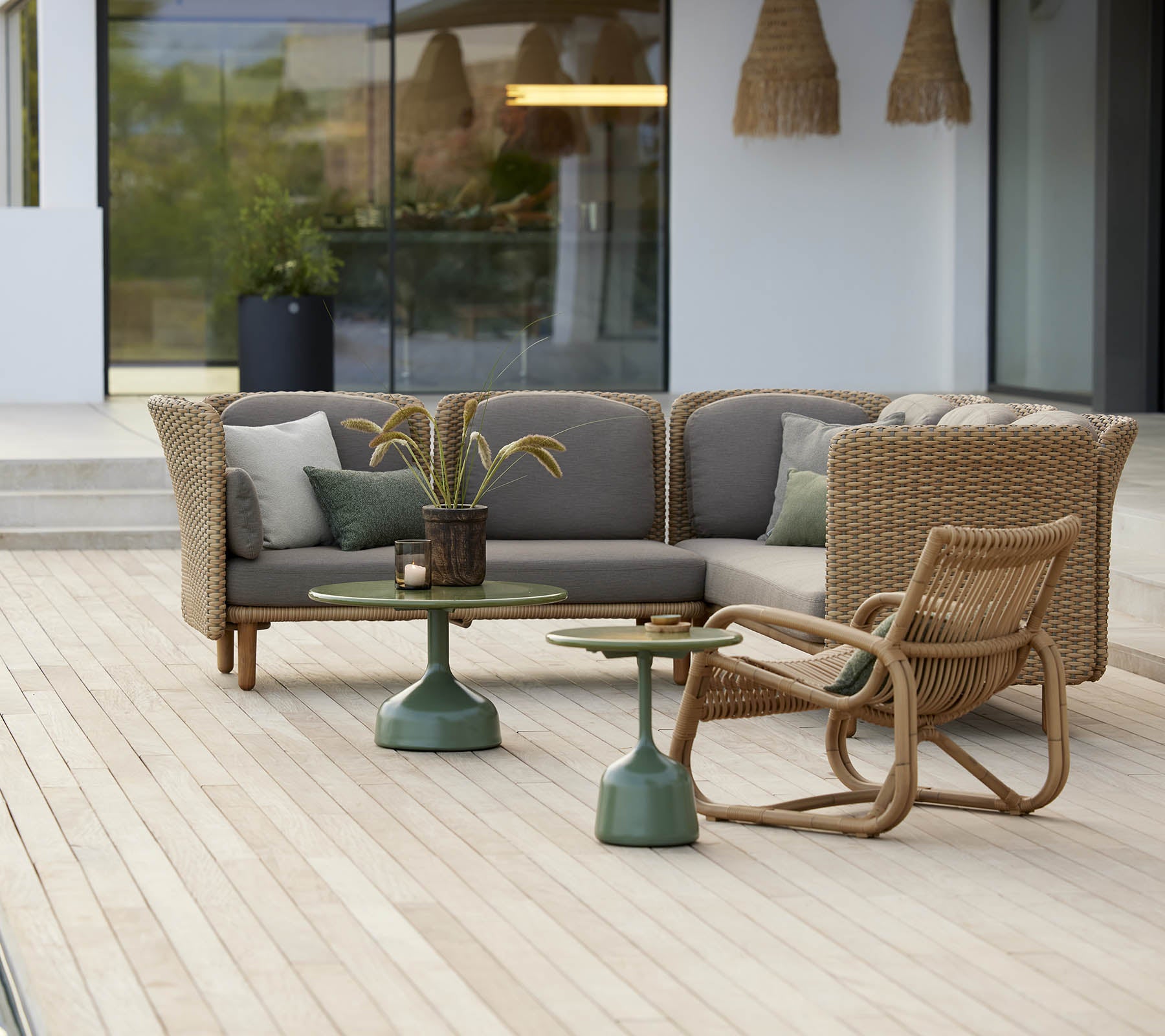 Stylish seating area featuring a curved lounge chair and a table with a green base, complemented by soft cushions and decorative elements.