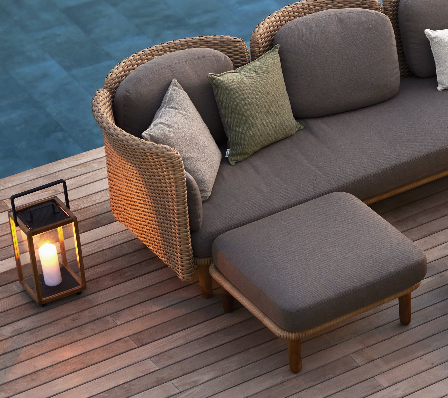 A cozy seating area featuring a sofa with cushions and a lantern, enhancing the ambiance with warm light.