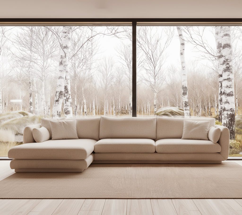 Beige modern sofa in a bright lounge setting with large windows.