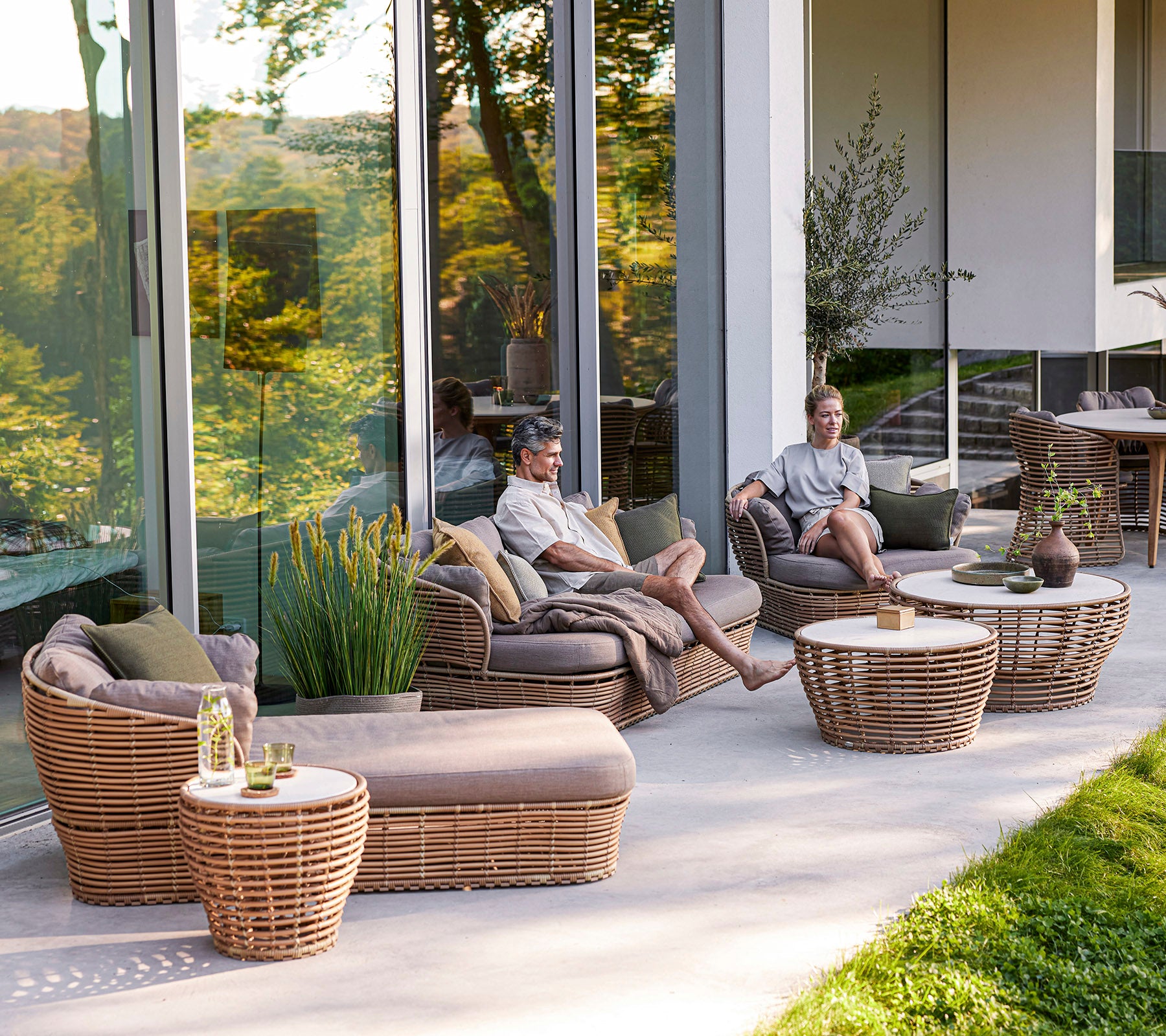 A relaxing seating area featuring woven furniture with cushions and low tables, where two people enjoy their time together.