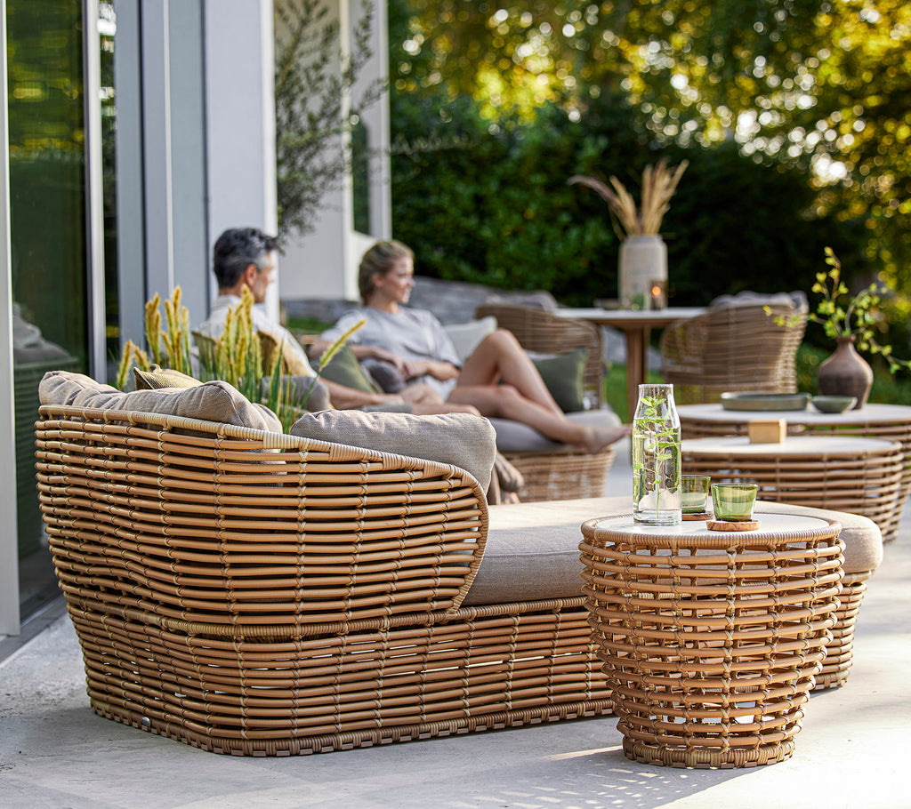 Stylish woven furniture set featuring a cozy seating area and tables, complemented by decorative plants and a relaxed atmosphere.