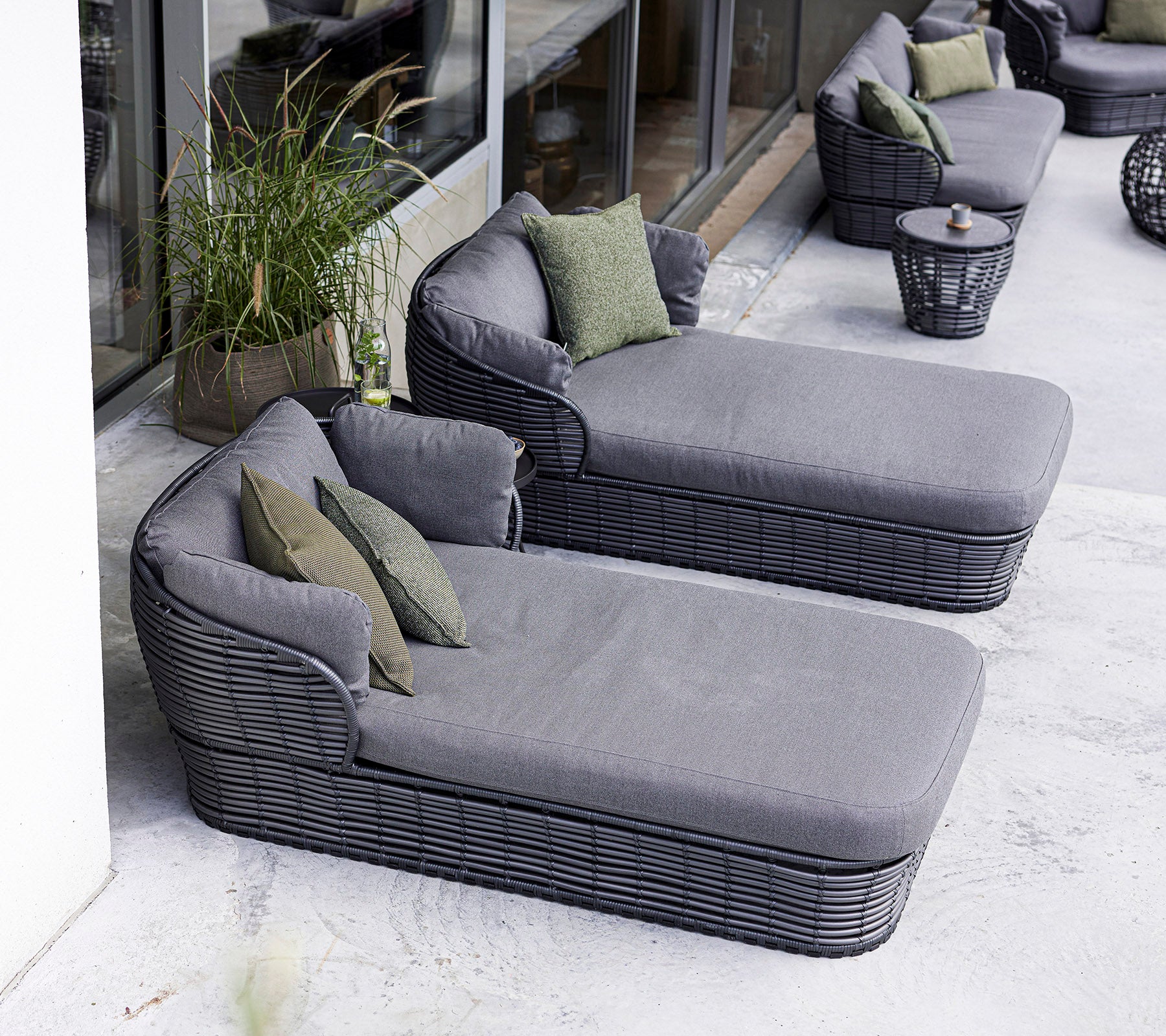 Two modern lounge chairs with plush gray cushions and green accent pillows, accompanied by a round side table.