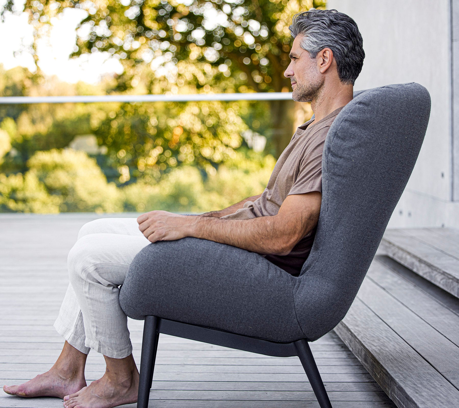 Man sitting comfortably in a modern chair with a sleek design, showcasing soft upholstery and an elegant, minimalist form.