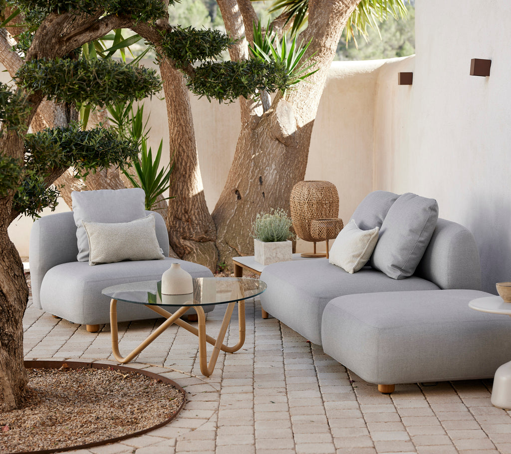 Contemporary grey sofa and chair with a glass table in a stylish outdoor lounge area.