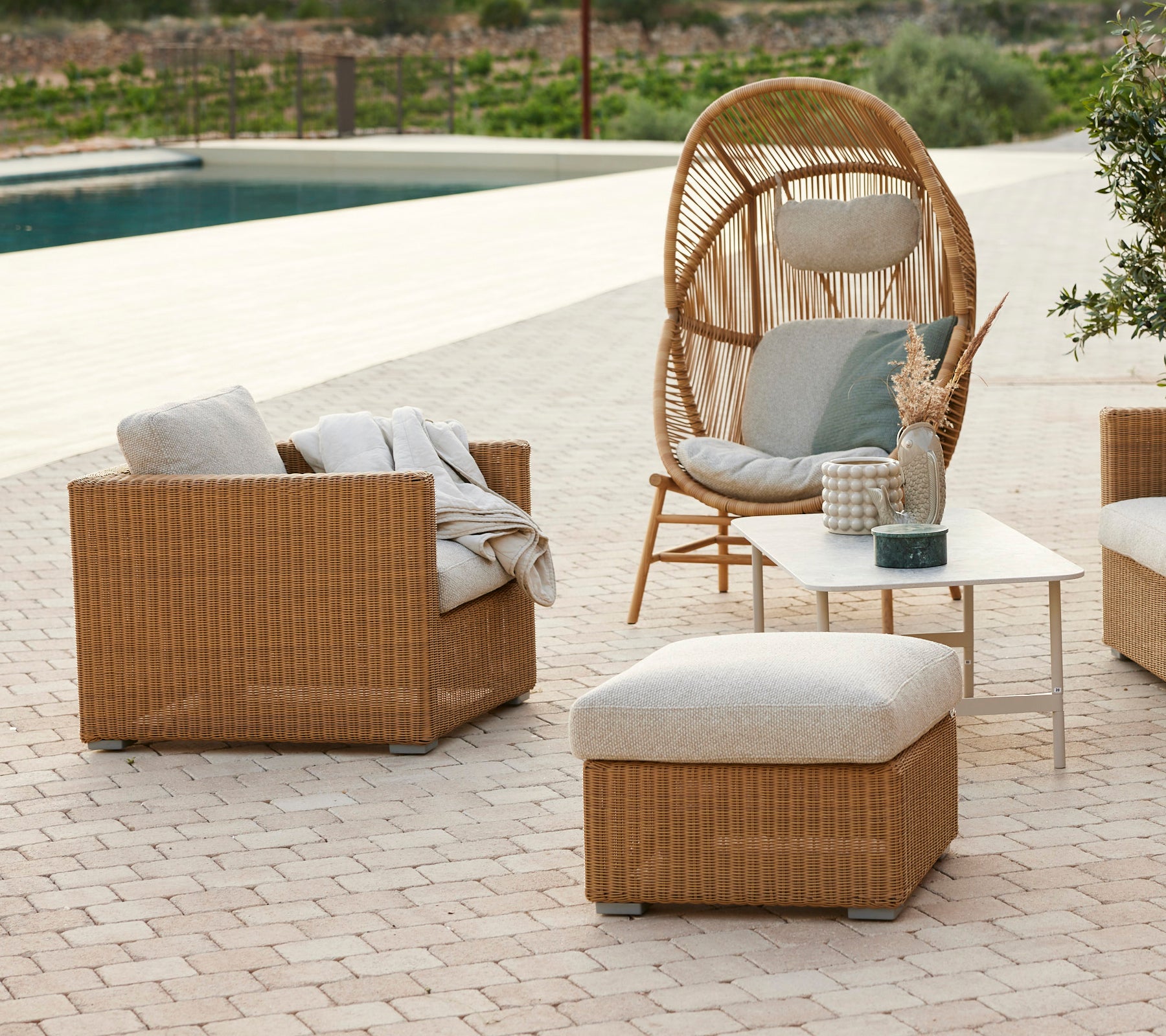 Modern lounge area with a rattan chair, grey cushions, rattan sofa, and a coffee table.