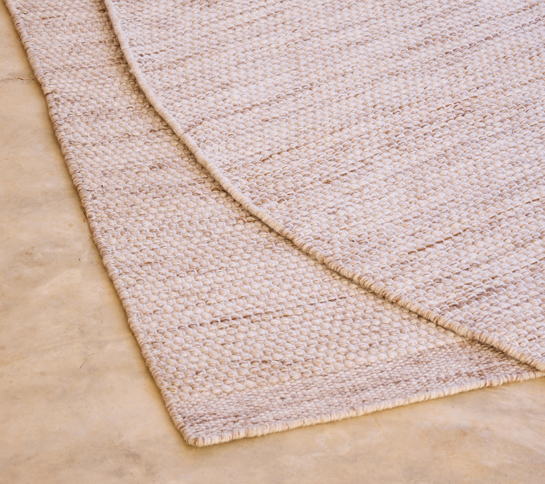 Beige rug with a textured pattern on a light-colored floor.