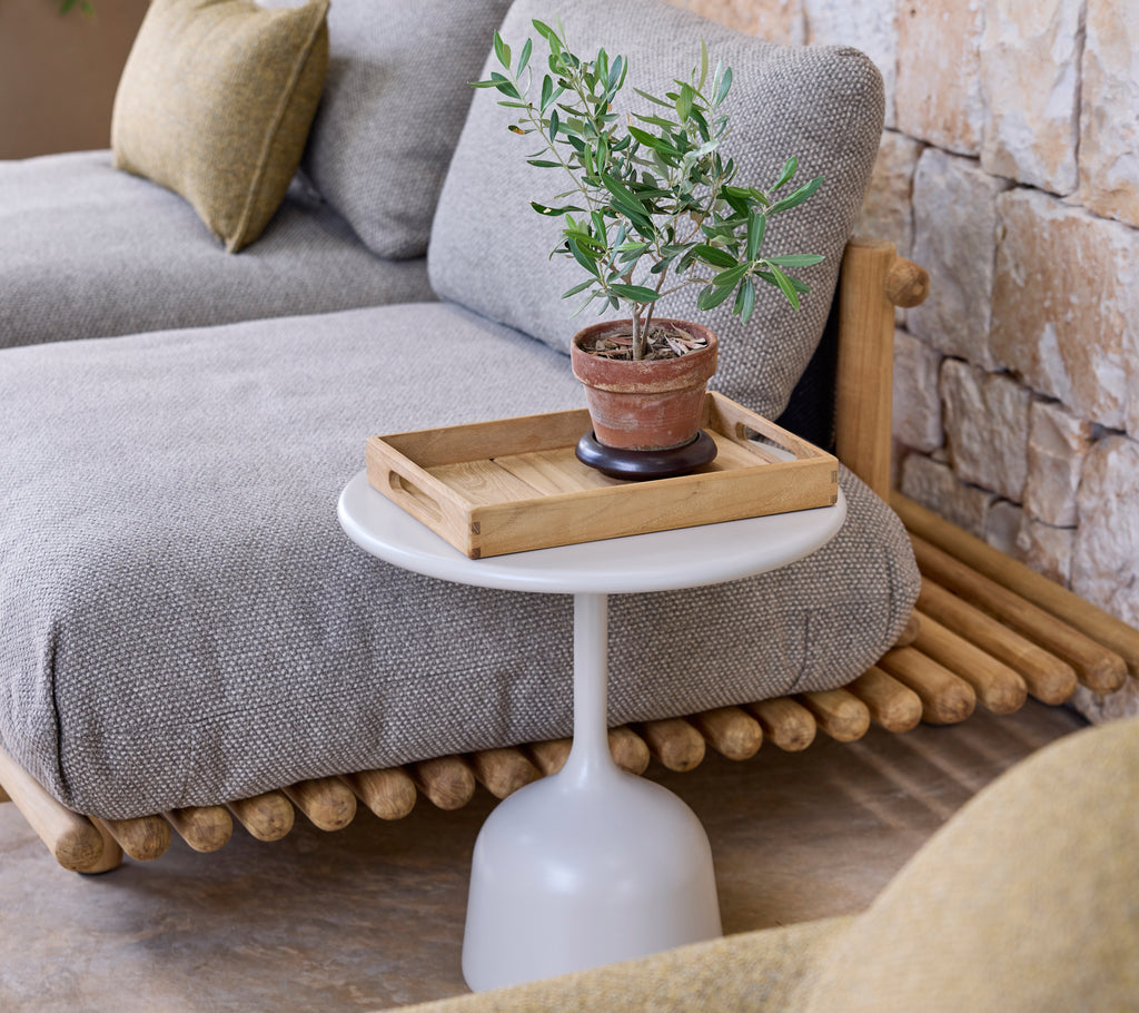 Modern lounge setup featuring a grey sofa, white side table, and a green plant.