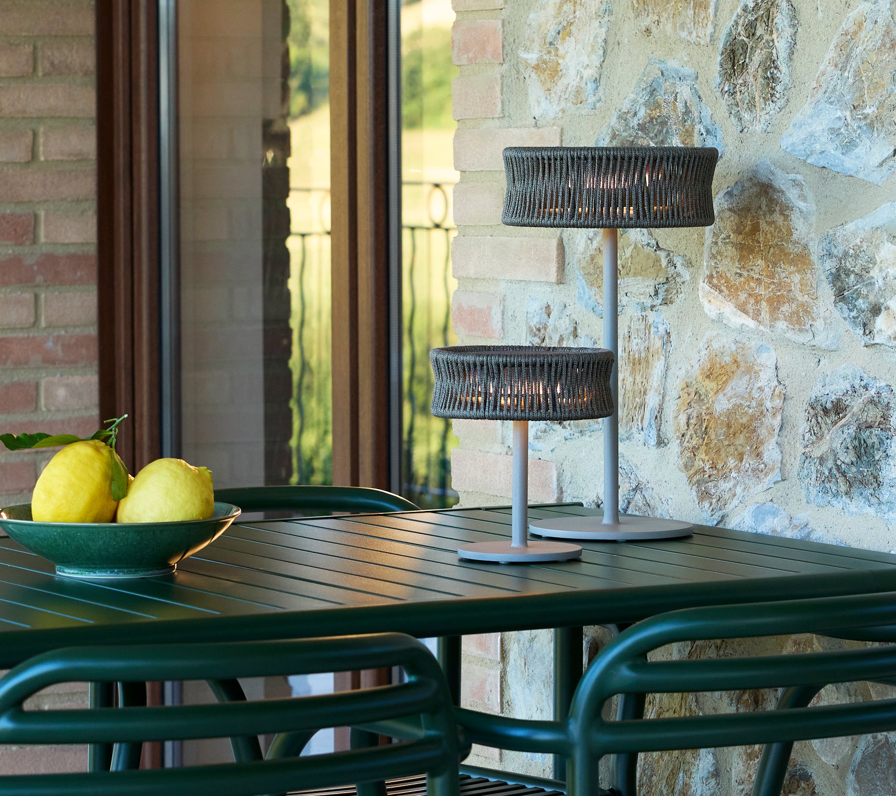 Small and medium illusion lamps on a table with a bowl of lemons, surrounded by stone and glass elements.