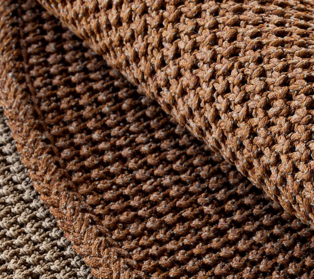Close-up view of a textured knit rug, showcasing rich shades of brown and intricate weaving patterns.
