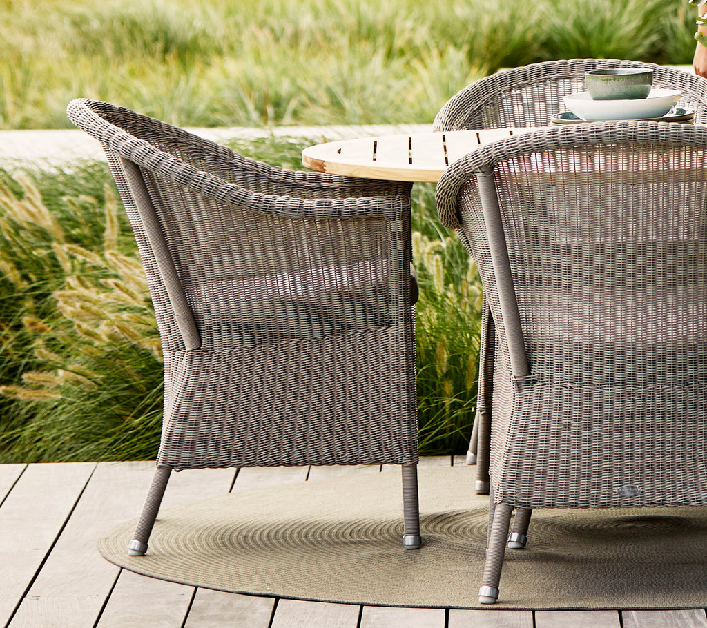 Taupe Lansing chairs with textured woven design, paired with a natural wood table and surrounded by lush greenery.
