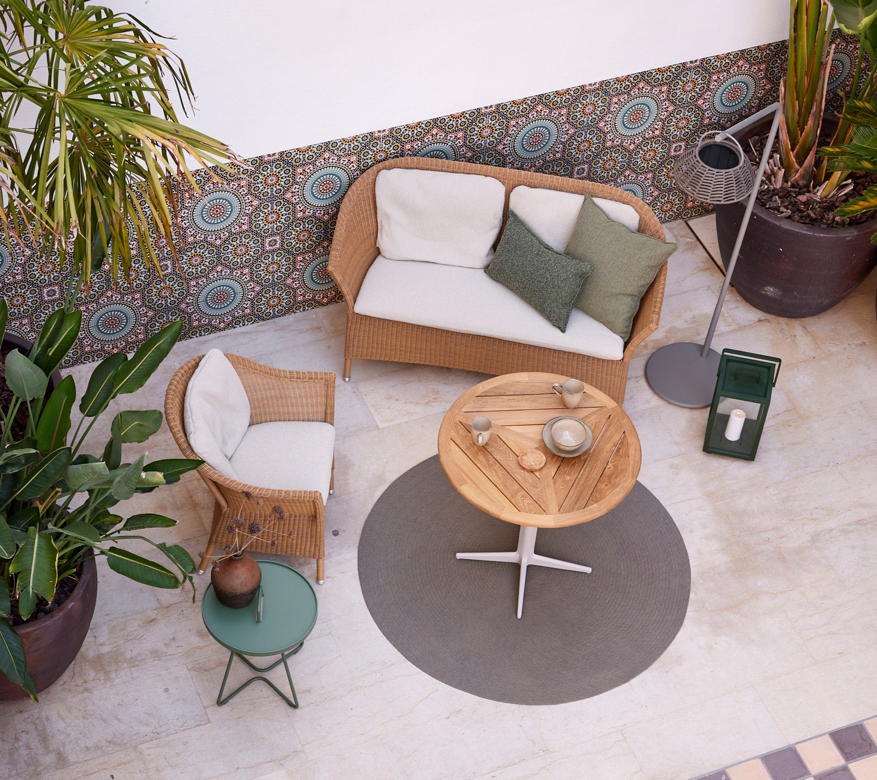 A cozy setting featuring a Lansing sofa and chair, a circular table, and greenery, creating a relaxed atmosphere. Perfect for leisure.