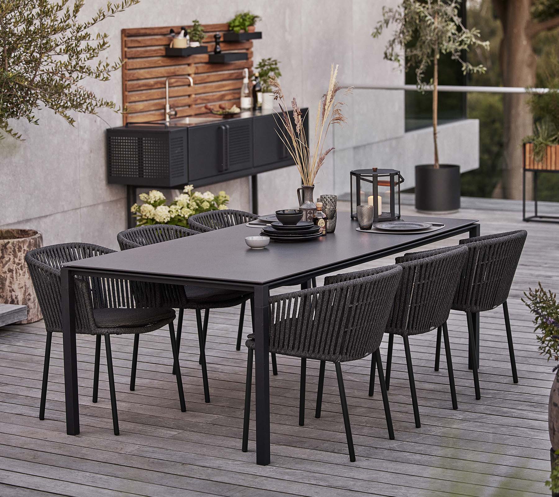 A sleek black table set with six Moments chairs, featuring tableware and decorative elements for an inviting dining experience.