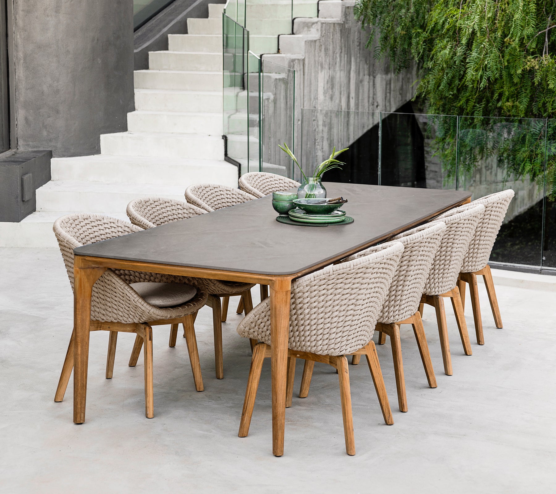 Modern brown dining table with woven chairs in a contemporary setting.