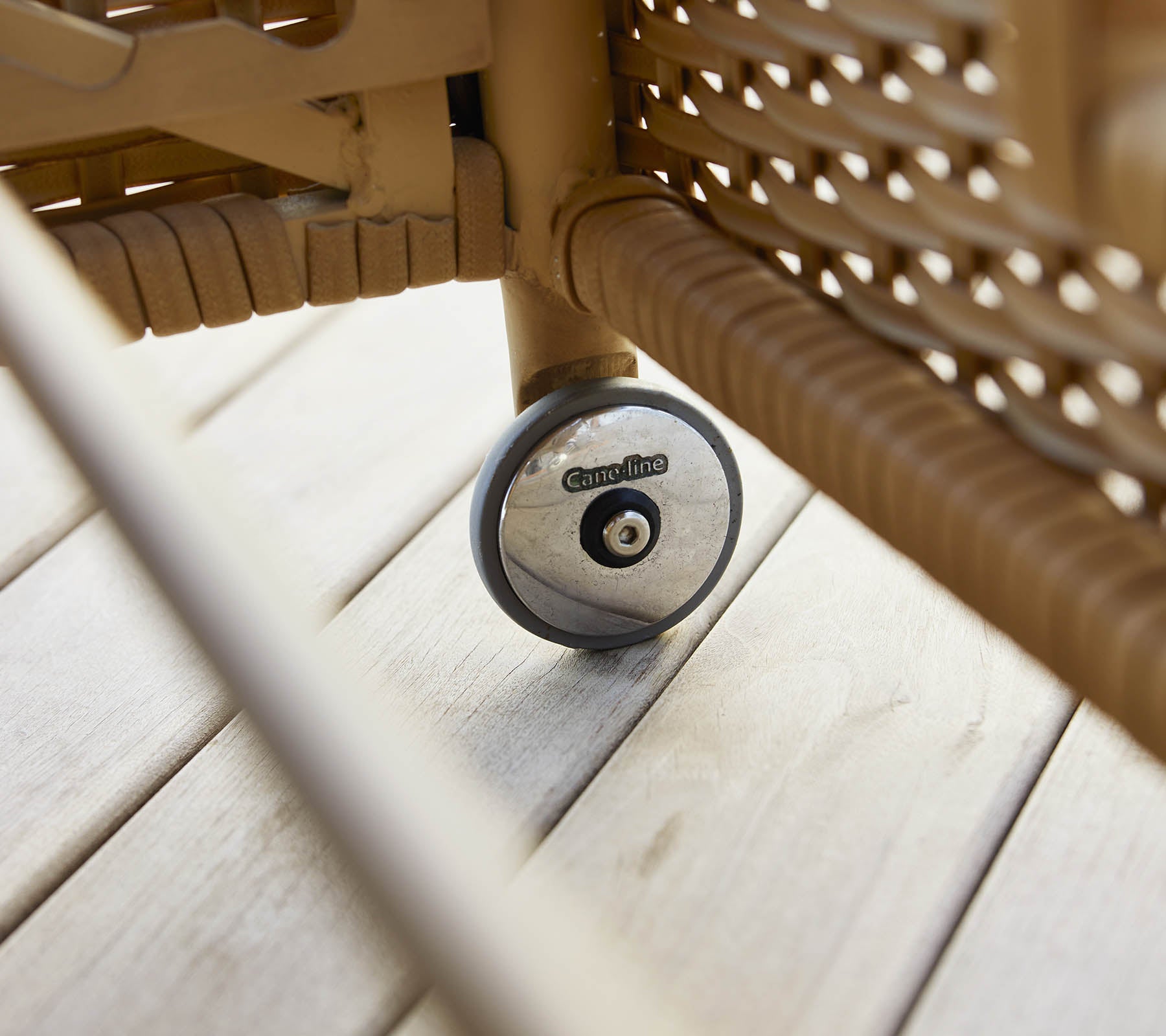 A close-up of the wheel of a rest sunbed, showcasing its design and texture against a wooden surface.