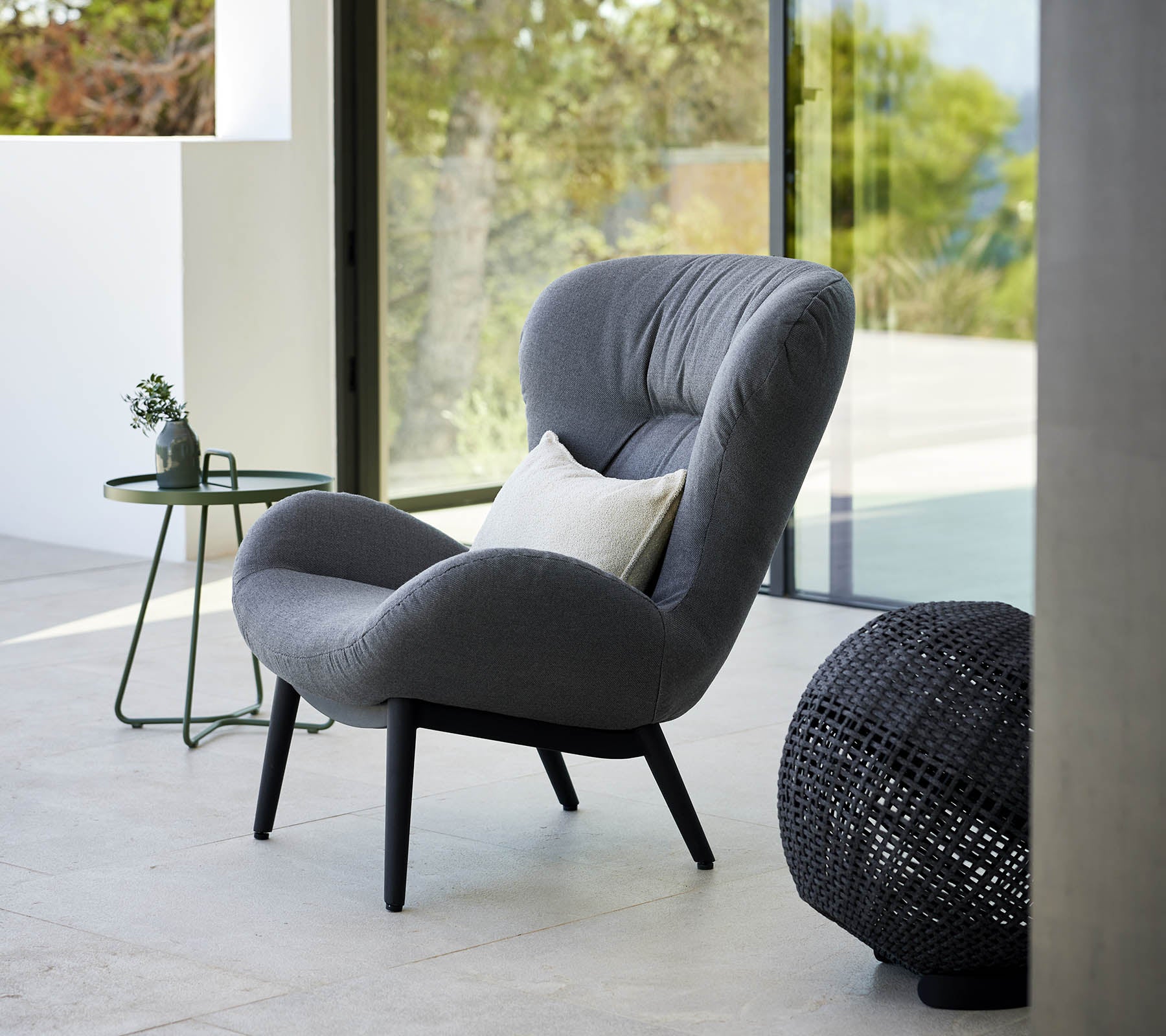 A serene lounge chair with a modern design, featuring plush upholstery and elegant legs, accompanied by a small side table and decorative accents.
