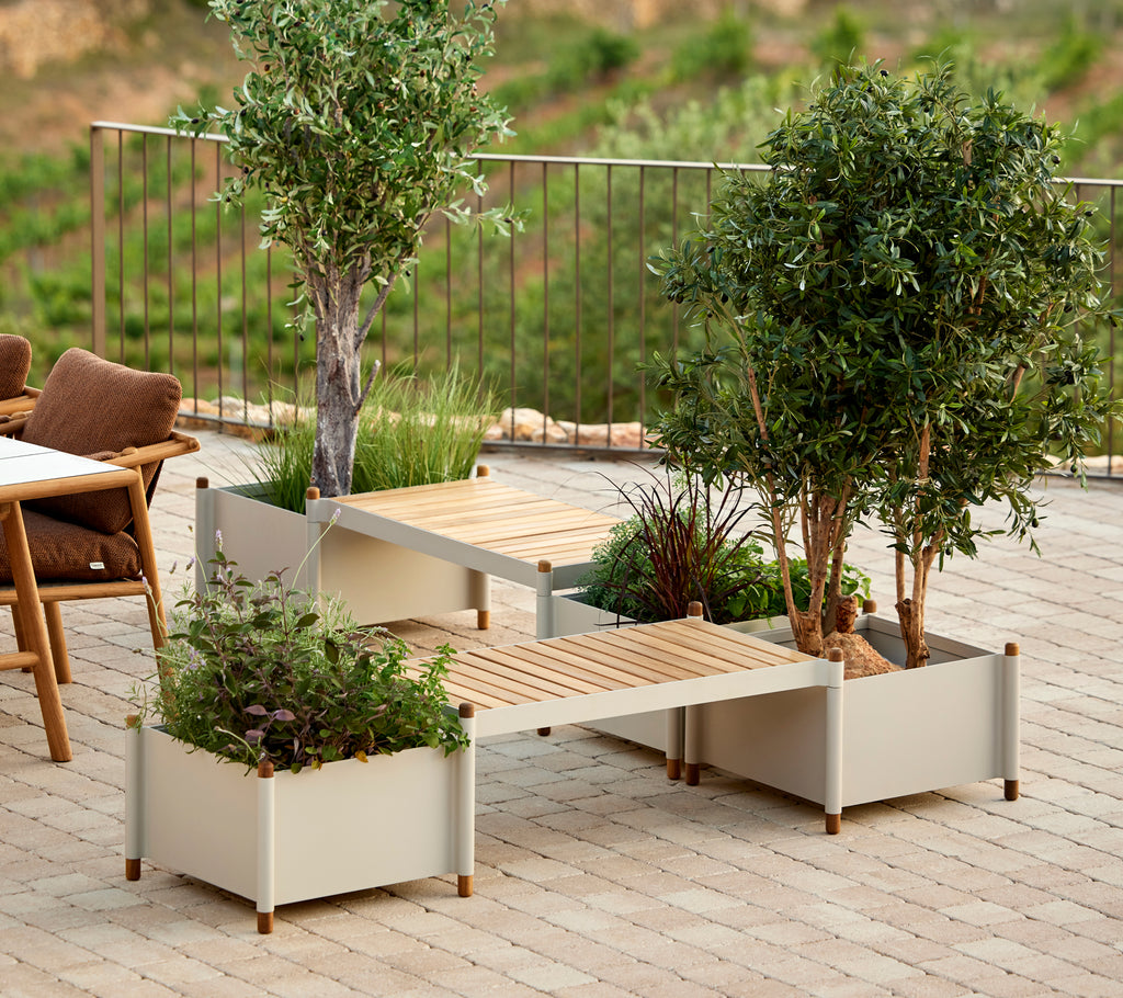 A sleek bench featuring two planters, adorned with greenery, enhancing outdoor aesthetics with a natural touch.