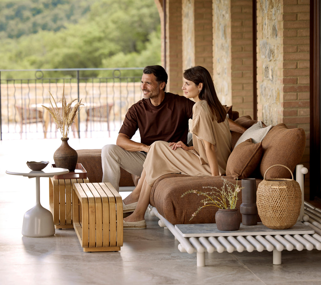 A couple sits together on a stylish sofa, surrounded by decorative elements including a mellow coffee table and tasteful accents.