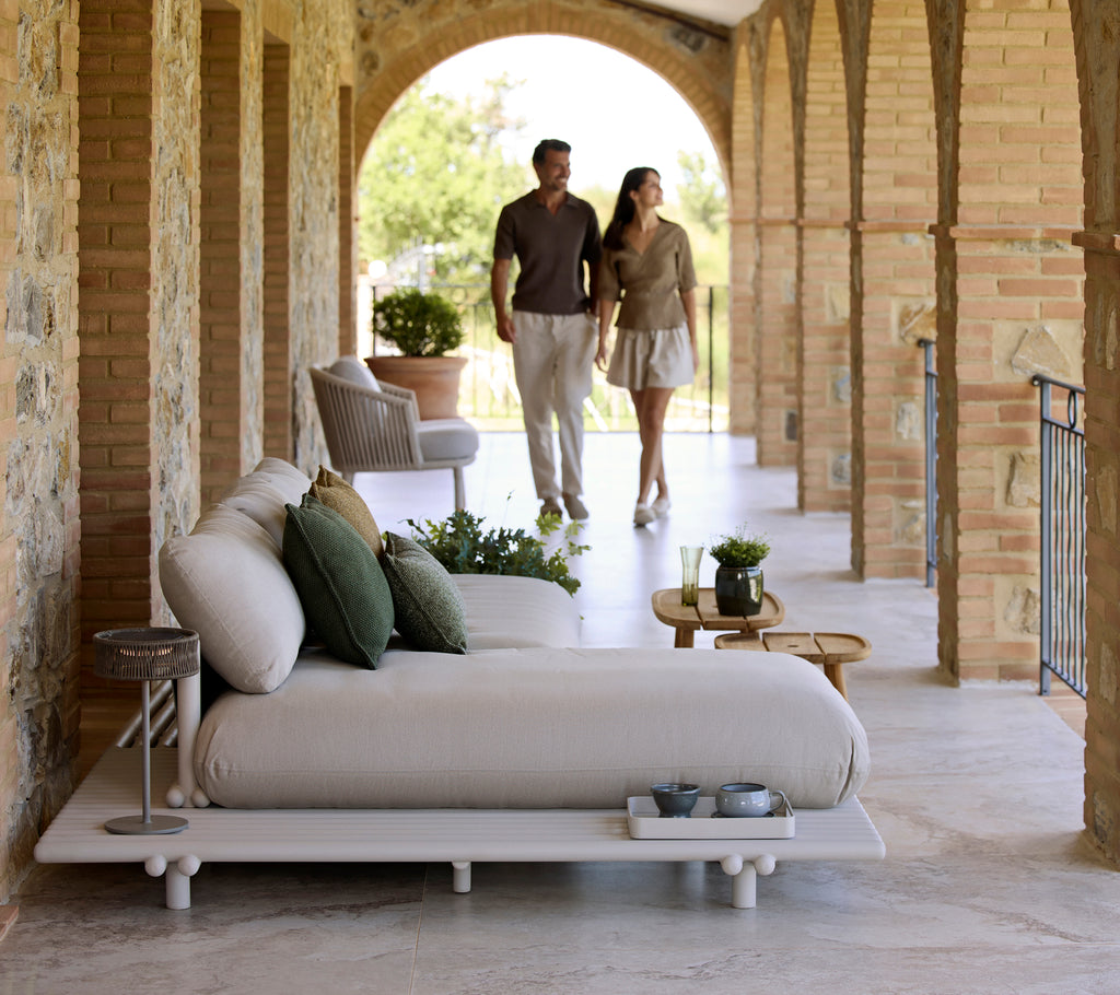 A stylish seating area featuring a plush sofa with cushions, an illusion lamp, and a royal coffee table, complemented by greenery.