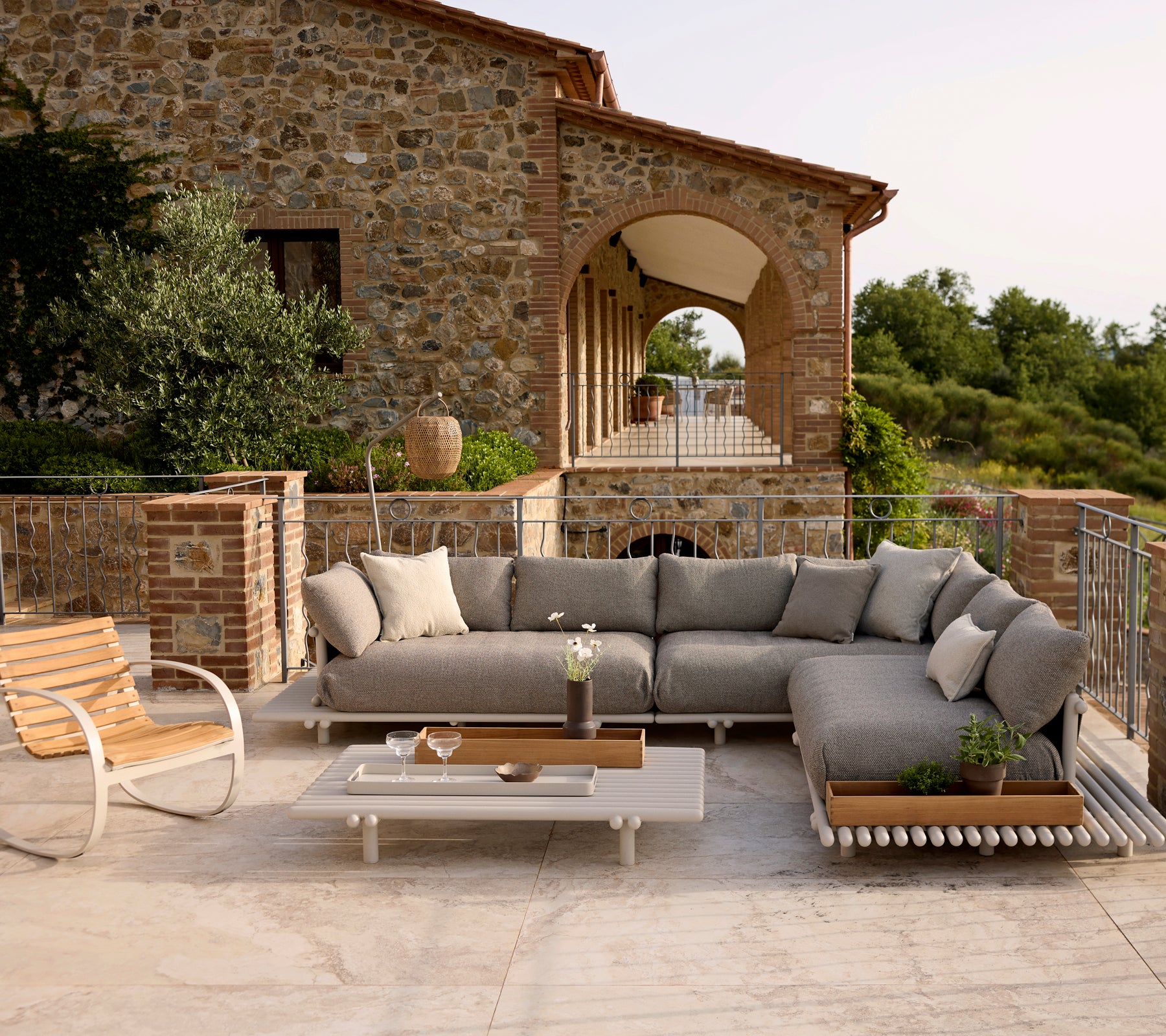 Lounge seating with plush cushions, complemented by a stylish rocking chair and a coffee table, set against a scenic backdrop.