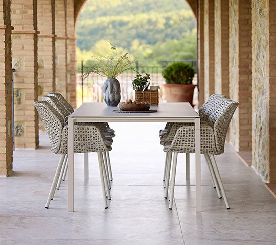 A stylish dining setup featuring Vibe dining chairs and a Pure dining table in a soft sand color, with decorative elements.