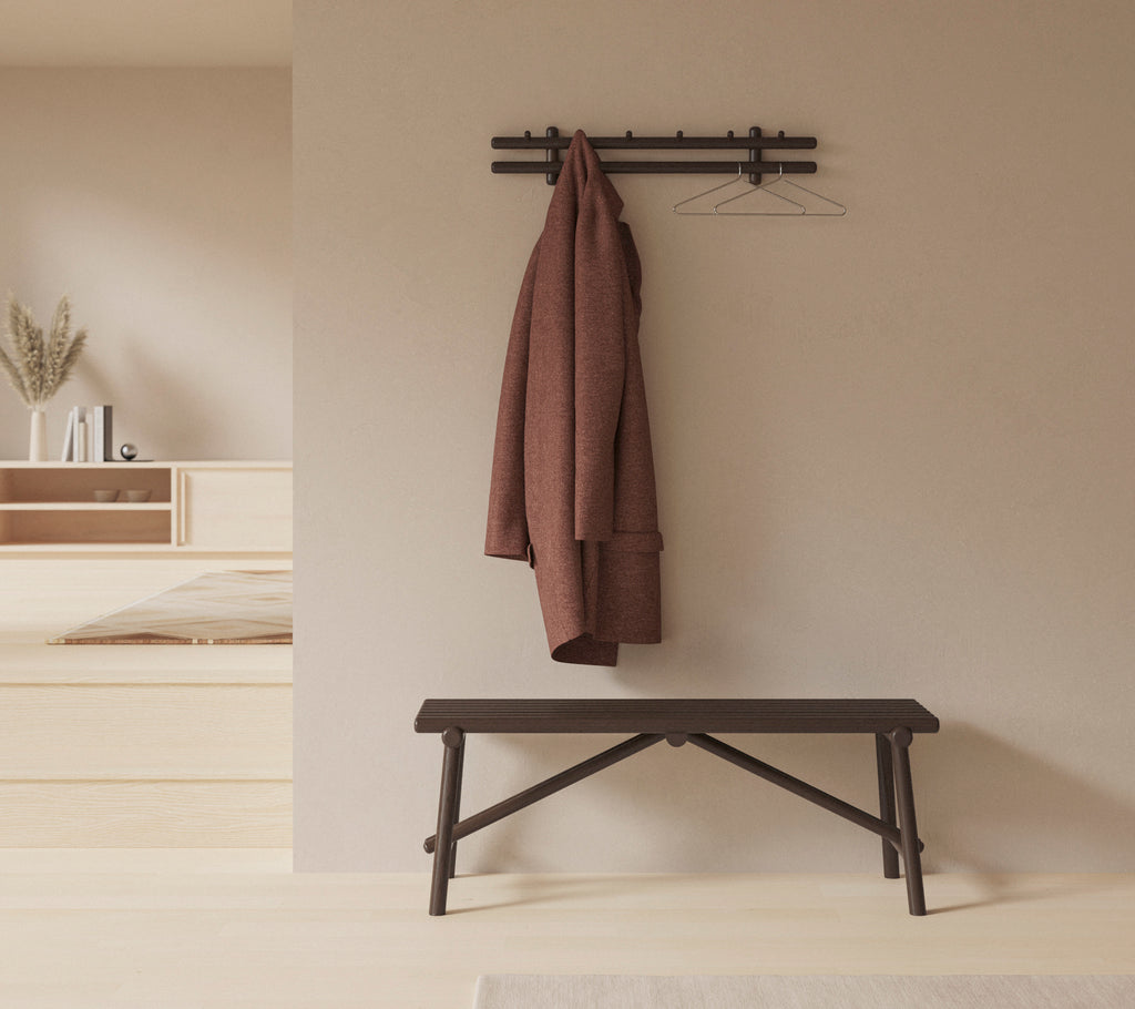A minimalist setting featuring a wooden bench and a coat hanging on a wall-mounted rack, enhancing the space's simplicity and functionality.
